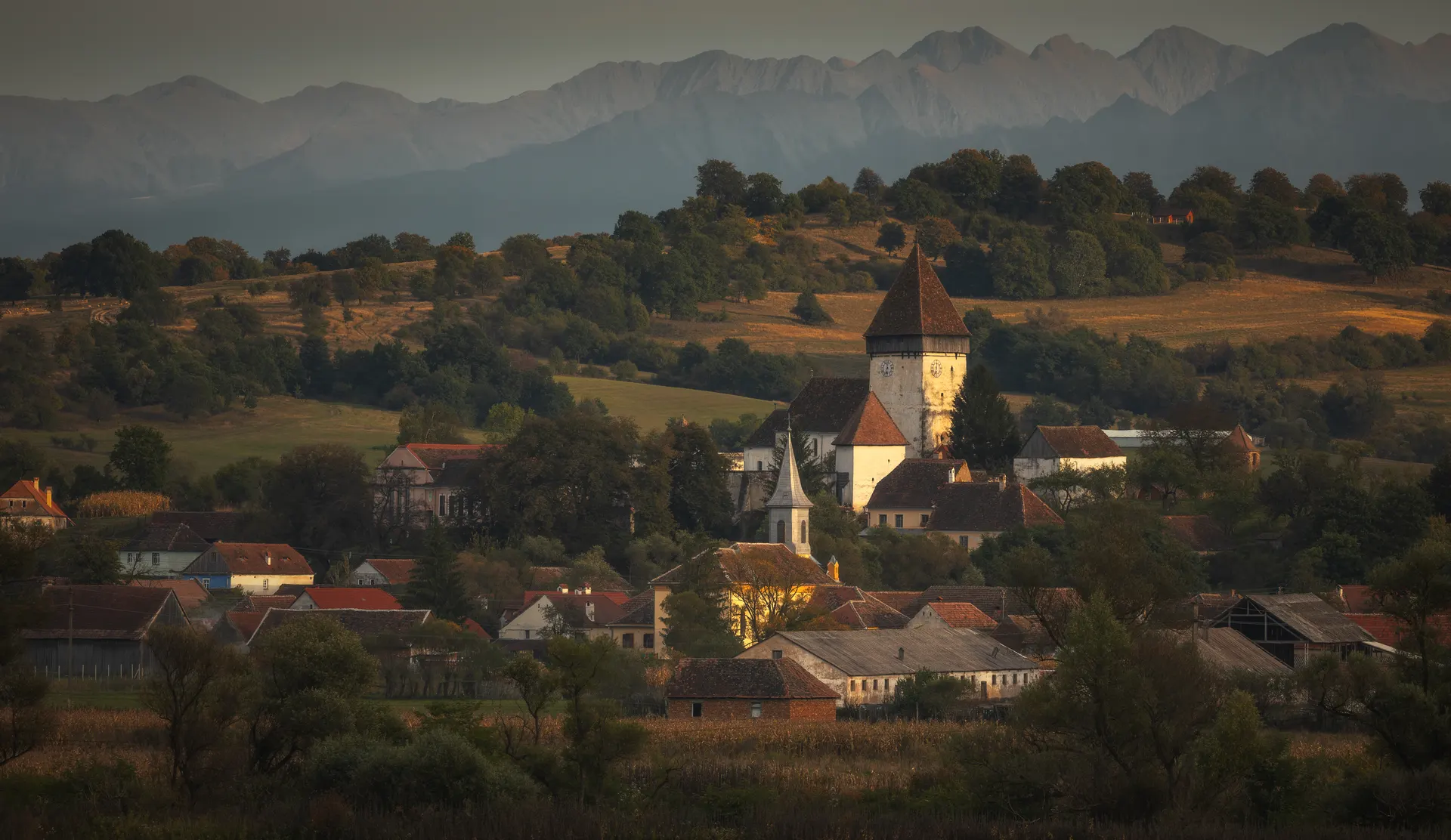 Village traditionnel de Transylvanie au coucher du soleil avec montagnes en arrière-plan